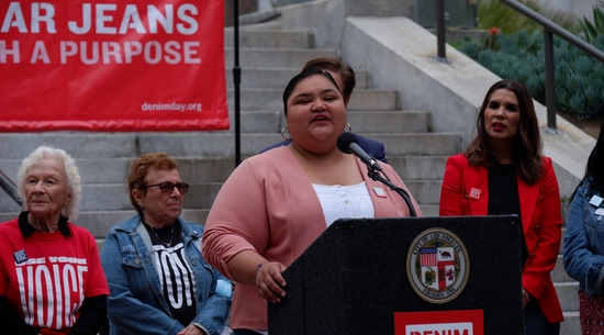 Councilmember Hernandez in a pink cardigan speaks at the podium at Denim Day