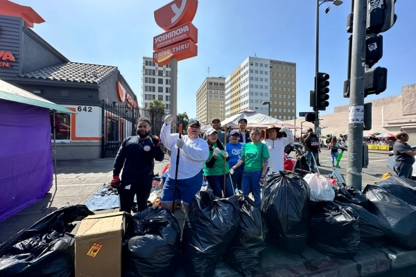 Group of people on sidewalk celebrating successful community clean up
